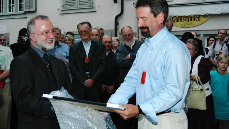 John Sharp, Vertreter der US-Mennoniten, erhält bei der Enthüllung der Gedenktafel an der Schipfe von Pfr. Ruedi Reich eine Kopie.